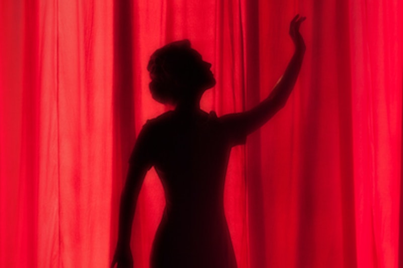 Shadow of a woman behind a red curtain