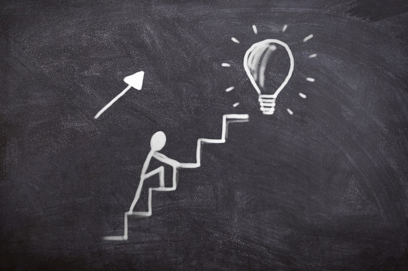 A person climbing up the stairs towards an idea