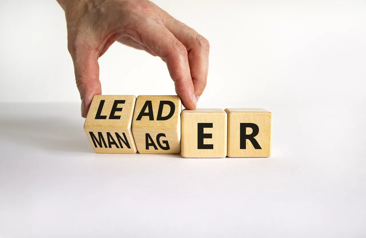 A hand arranging blocks to form the word leader or manager