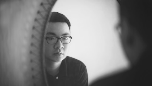 A person looking at his reflection in the mirror